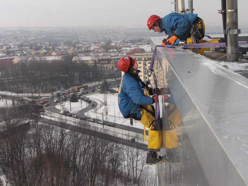 photo de deux hommes travaillant sur un bâtiment en hauteur